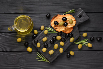 Black and green olives on a dark wooden black background.