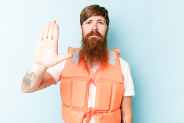Young caucasian man wearing life jacket isolated on blue background standing with outstretched hand...