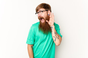 Young caucasian red-haired man isolated on white background trying to listening a gossip.