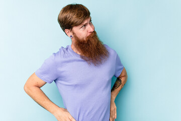 Young caucasian red-haired man isolated on blue background dreaming of achieving goals and purposes