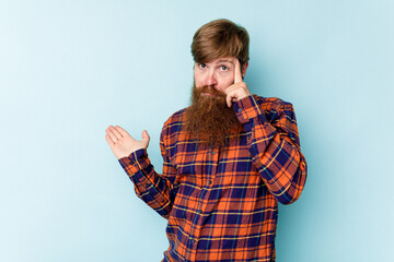 Young caucasian red-haired man isolated on blue background showing a disappointment gesture with forefinger.