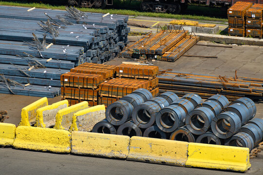 industrial infrastructure of the seaport, a warehouse by the sea with coils of wire, cranes and railway wagons, iron billets, metal structures, the concept of marine cargo transportation