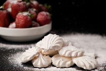Meringue close up and strawberries in a plate on a black background. Fruit desserts.