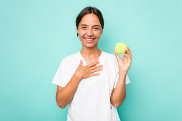 Young hispanic physiotherapy holding a tennis ball isolated on blue background laughs out loudly...