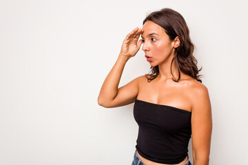 Young hispanic woman isolated on white background looking far away keeping hand on forehead.