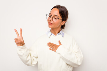 Young hispanic woman isolated on white background taking an oath, putting hand on chest.