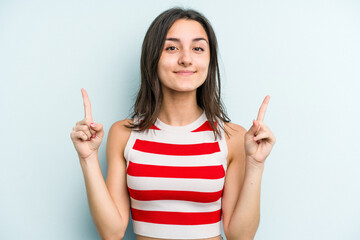 Young caucasian woman isolated on blue background indicates with both fore fingers up showing a blank space.