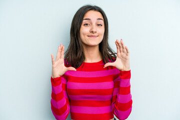 Young caucasian woman isolated on blue background holding something with palms, offering to camera.