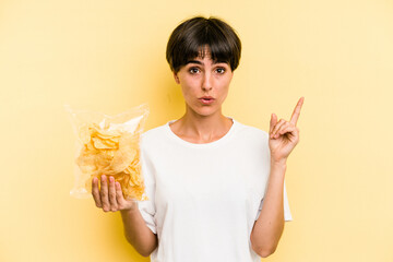 Young caucasian man holding crisps isolated on yellow background having some great idea, concept of creativity.