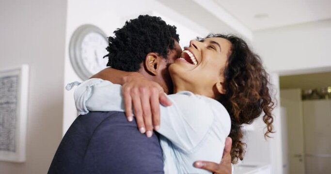 Happy, cheerful and loving couple huggging and celebrating good news while standing together at home. African man and supporting wife feeling positive and excited about new job success or promotion