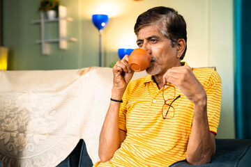 thoughtful senior Grandfather drinking tea during morning at home - concepts of refreshment, relaxation and loneliness.