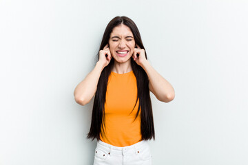 Young caucasian woman isolated on white background covering ears with hands.