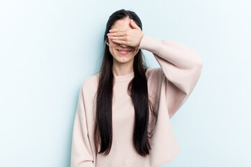 Young caucasian woman isolated on blue background covers eyes with hands, smiles broadly waiting for a surprise.