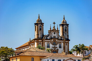 Fototapeta na wymiar Baroque style historic church tower emerging from behind old houses in Ouro Preto city in Minas Gerais state, Brazil