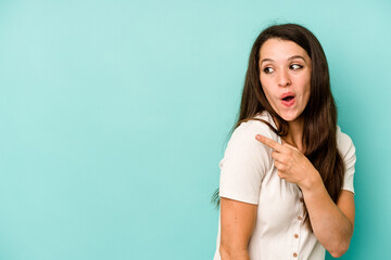 Young caucasian woman isolated on blue background points with thumb finger away, laughing and carefree.