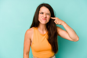 Fototapeta premium Young caucasian woman isolated on blue background covering ears with hands.