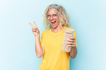 Middle age caucasian woman holding a chickpeas jar isolated on blue background joyful and carefree...