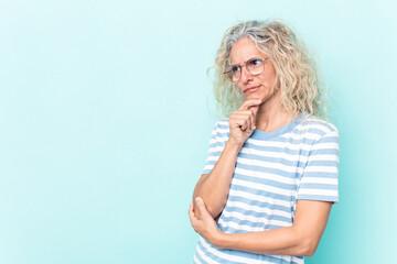 Middle age caucasian woman isolated on blue background looking sideways with doubtful and skeptical expression.