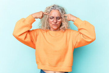 Middle age caucasian woman isolated on blue background focused on a task, keeping forefingers pointing head.