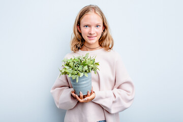 Caucasian teen girl holding a plant isolated on blue background happy, smiling and cheerful.