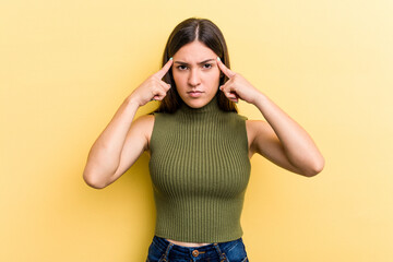 Young caucasian woman isolated on yellow background focused on a task, keeping forefingers pointing head.
