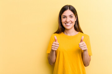 Young caucasian woman isolated on yellow background smiling and raising thumb up