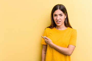 Young caucasian woman isolated on yellow background pointing to the side