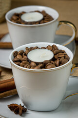 Tea candle in a cup with coffee beans. Aromatic tea candle.