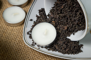 Tea candle in a cup with loose tea. Aromatic tea candle.