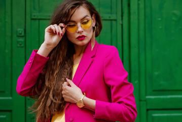Fashionable confident woman wearing trendy summer outfit with yellow cat eye sunglasses, golden...