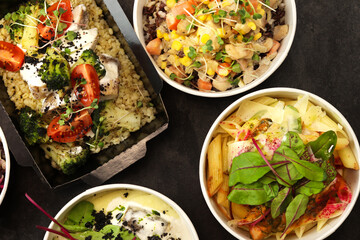 Ready healthy food menu in lunch boxes with fish, meat and vegetable packages as daily courier delivery diet plan isolated on black table background. The concept of ordering takeaway containers.