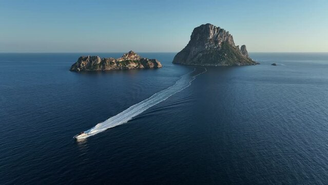 Aerial video of Es Vedra and Es Vedranell islands in Ibiza, yacht returning from visiting it sailing the sea.