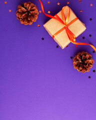 Flat lay of brown gift box with a orange satin ribbon bow and stars shapes pine cone on vibrant...