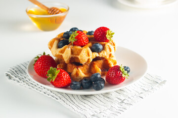 Fresh homemade food of berry Belgian waffles with honey, chocolate, strawberry, blueberry, maple syrup and cream. Healthy dessert breakfast concept with coffee