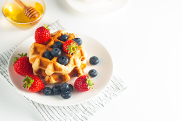 Fresh homemade food of berry Belgian waffles with honey, chocolate, strawberry, blueberry, maple syrup and cream. Healthy dessert breakfast concept with coffee
