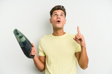 Young caucasian man holding a hand vacuum cleaner isolated on white background pointing upside with...