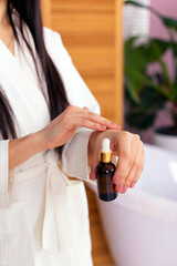 young woman in bathrobe uses body oil