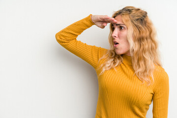 Young caucasian woman isolated on white background looking far away keeping hand on forehead.