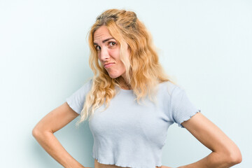 Young caucasian woman isolated on blue background confused, feels doubtful and unsure.