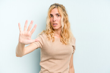 Young caucasian woman isolated on blue background being shocked due to an imminent danger