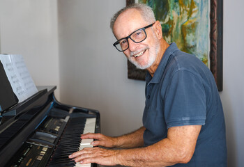 Man practicing playing the piano in the living room of his home after retirement from work.