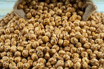 yellow roasted chickpeas in a straw sackon wood background