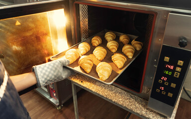 Hand is holding a bread tray out of the oven