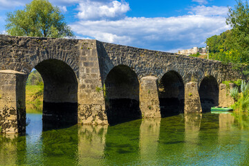 Fototapeta na wymiar The old stone bridge on the Dobra River, with a Novigrad Castle in the background, Croatia