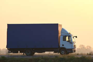 Cargo truck driving on highway hauling goods in evening. Delivery transportation and logistics...