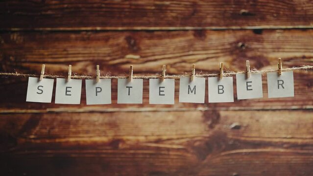 The word september. Letters on cards on wooden background. Autumn or nature and foliage. Concept of lettering and text or phrase.