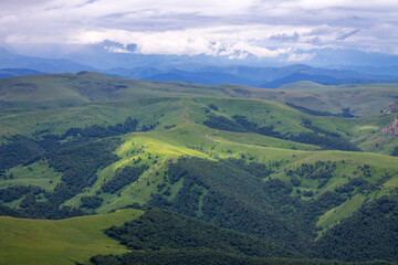 Fototapeta premium Beautiful landscape - panoramic view of green mountains and hills blurred in morning haze from bermamyt plateau in karachay-cherkessia Russia and copy space