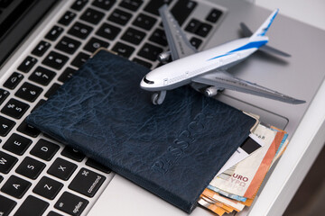 Top view of laptop computer, passport with euro banknotes and credit card, airplane.Travel and vacation, planning trip in the office or home, holiday tourism, agency tour