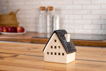Obraz na płótnie Canvas A model of a house on the background of kitchen furniture. The concept of buying a house, real estate mortgage, home interior