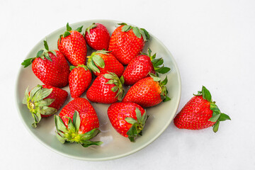 Red ripe strawberries in a light green bowl, light background, top view, healthy food, natural vitamins.Copy space